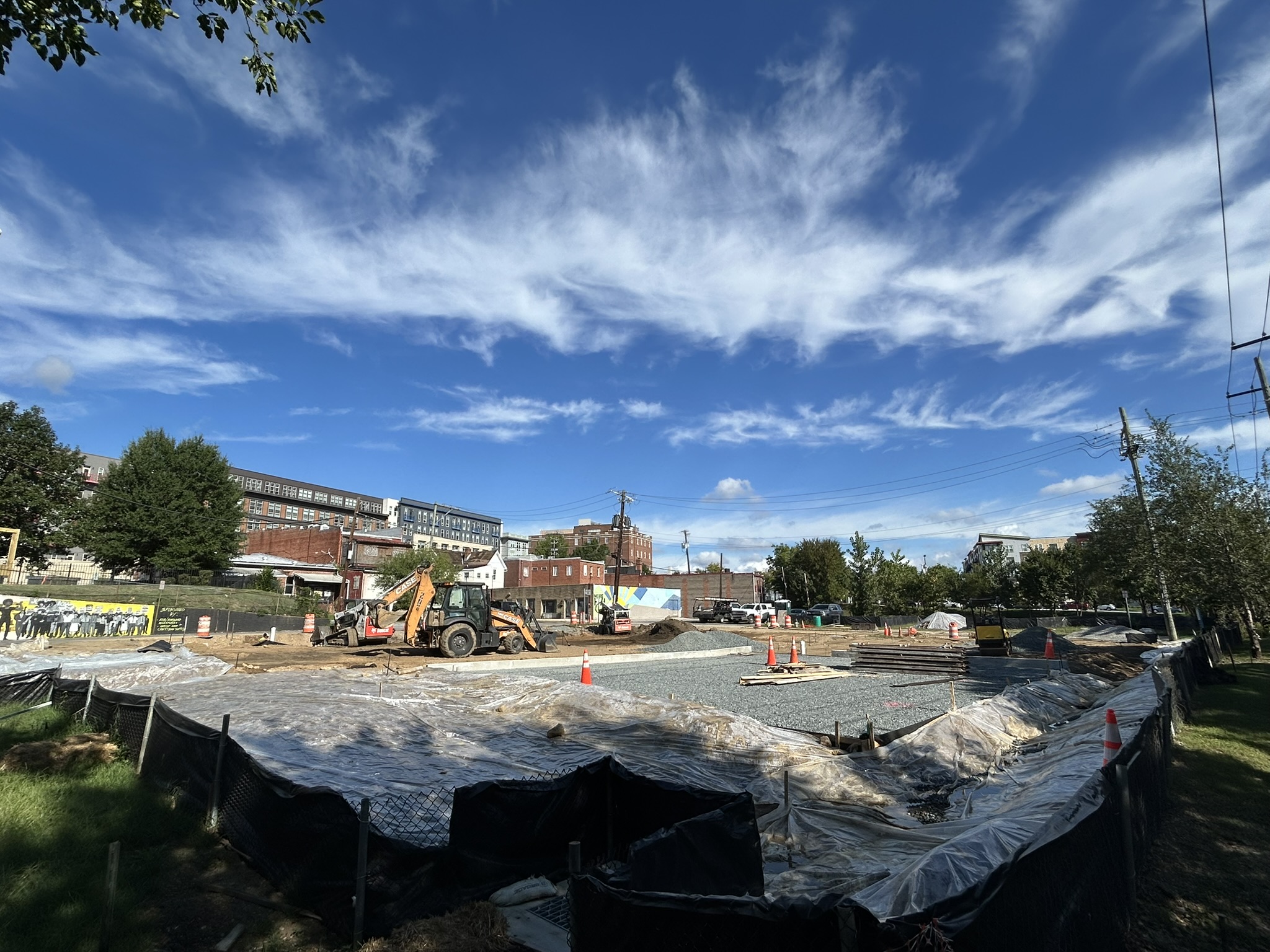 Wide angle view of the park construction site, with heavy equipment moving dirt and gravel.